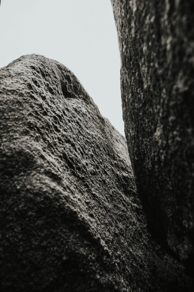 Dramatic close-up of rough textured boulders in grayscale, emphasizing natural stone patterns.