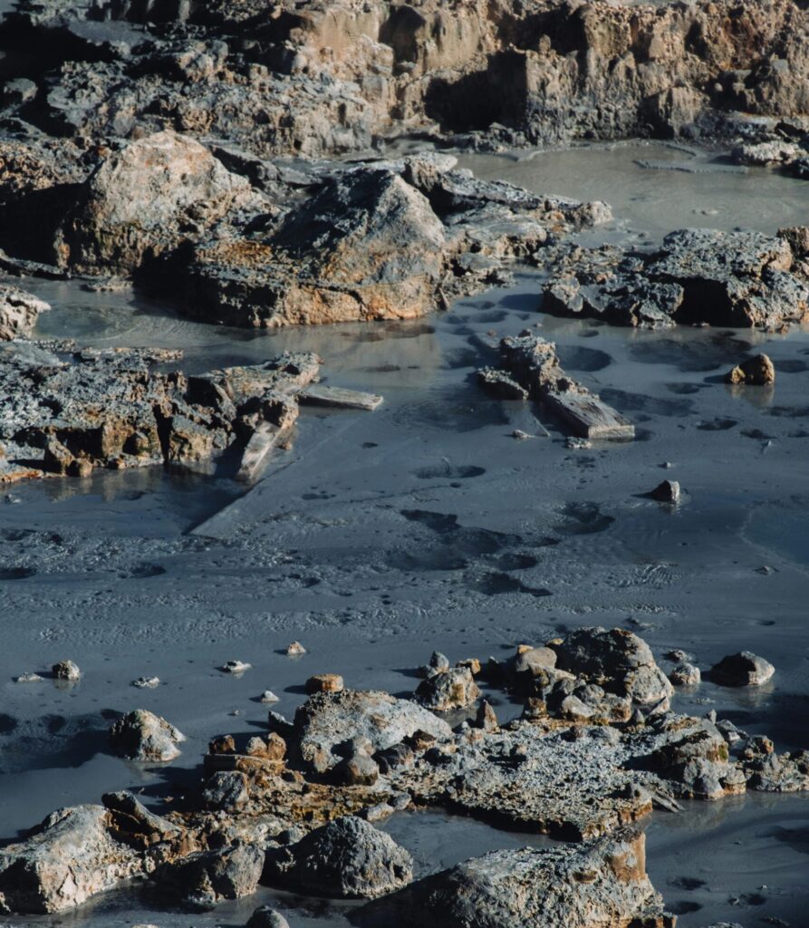 Sunlit, eroded rocks in a muddy and wet natural outdoor setting.