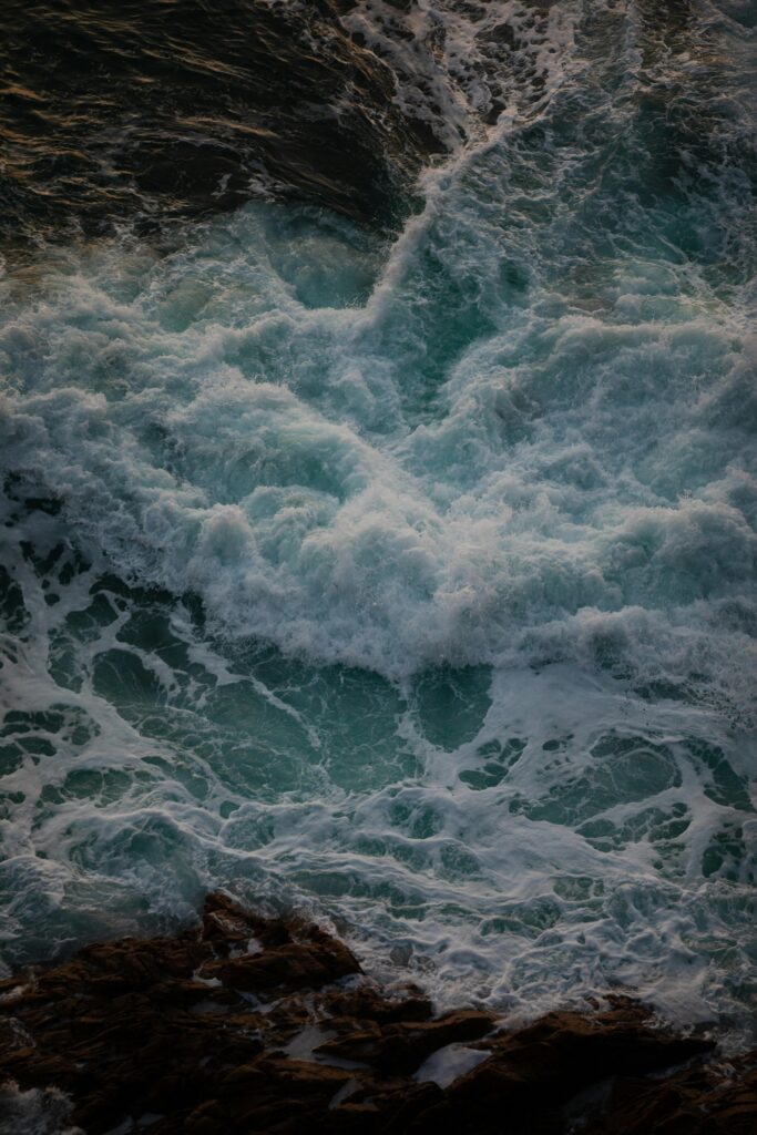 Powerful ocean waves crashing against a rocky shore creating sea foam and splash.