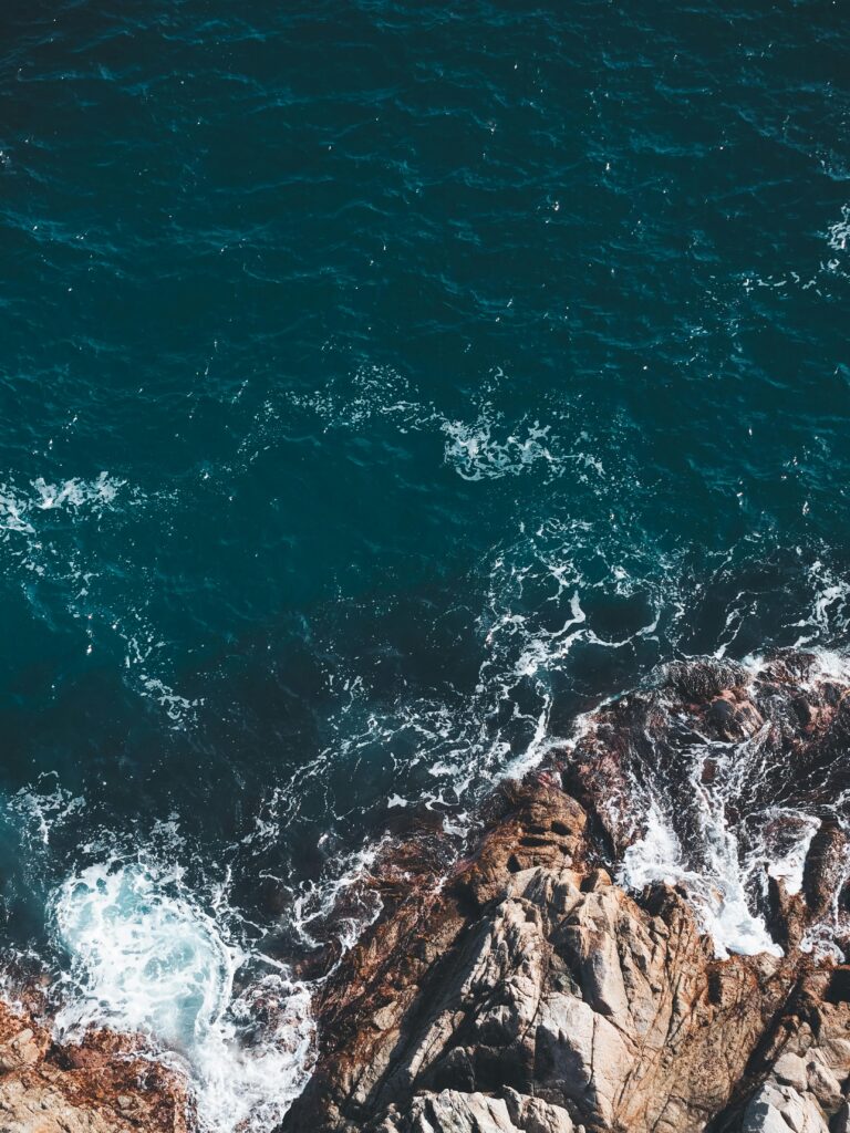 High-angle shot of waves crashing on a rocky coastline, perfect for nature backgrounds.